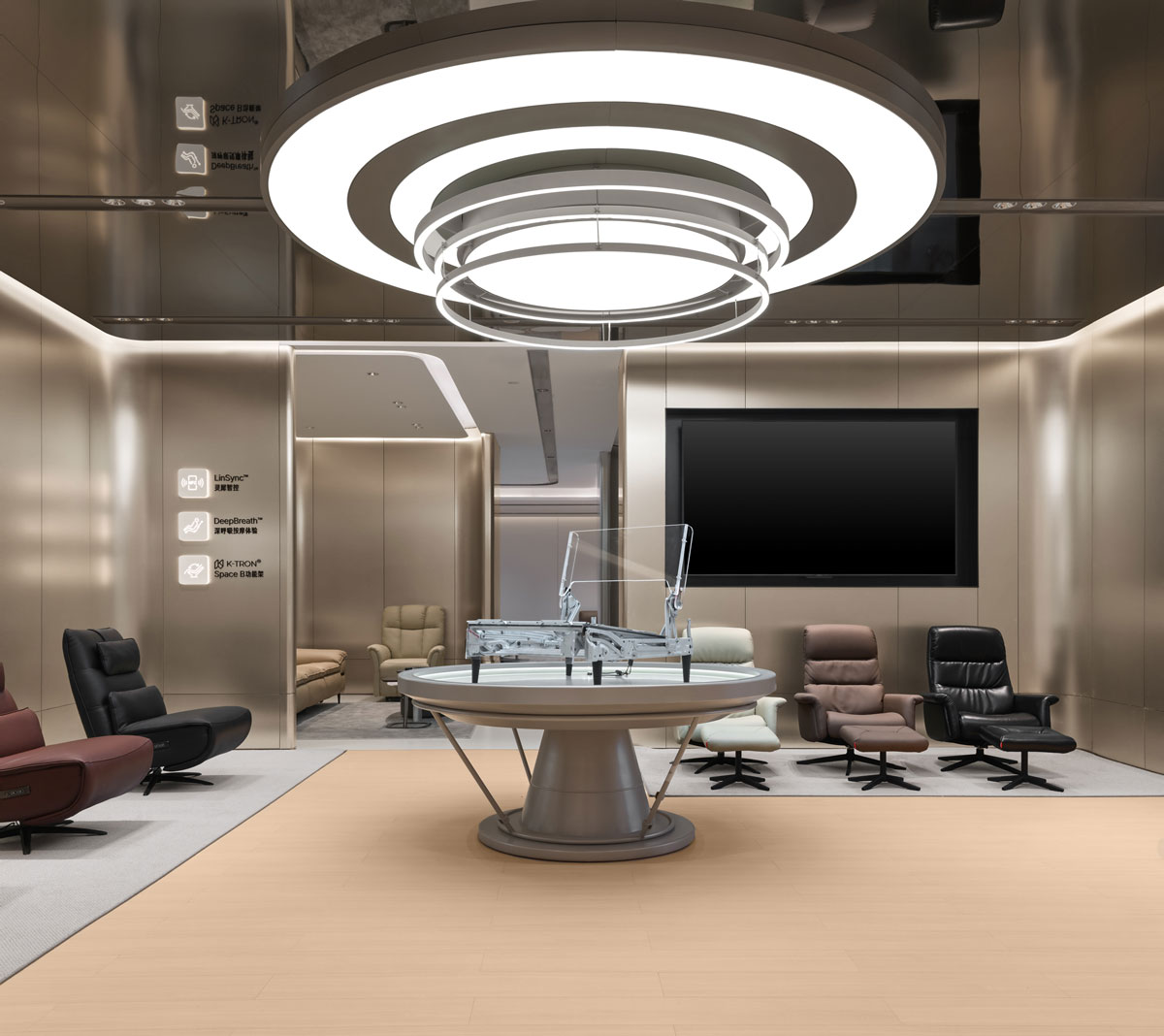 Central installation in the KUKA | JOY Living & Dining Showroom displaying the sofa structural system, a circular exhibition island, lounge chairs and integrated ring lighting.