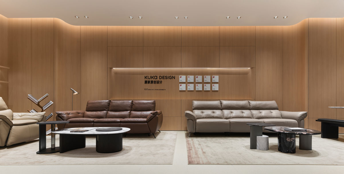 Living area of the KUKA | JOY Living & Dining Showroom in Hangzhou with leather sofas, coffee tables, wood wall panels and integrated lighting designed by STILL YOUNG.