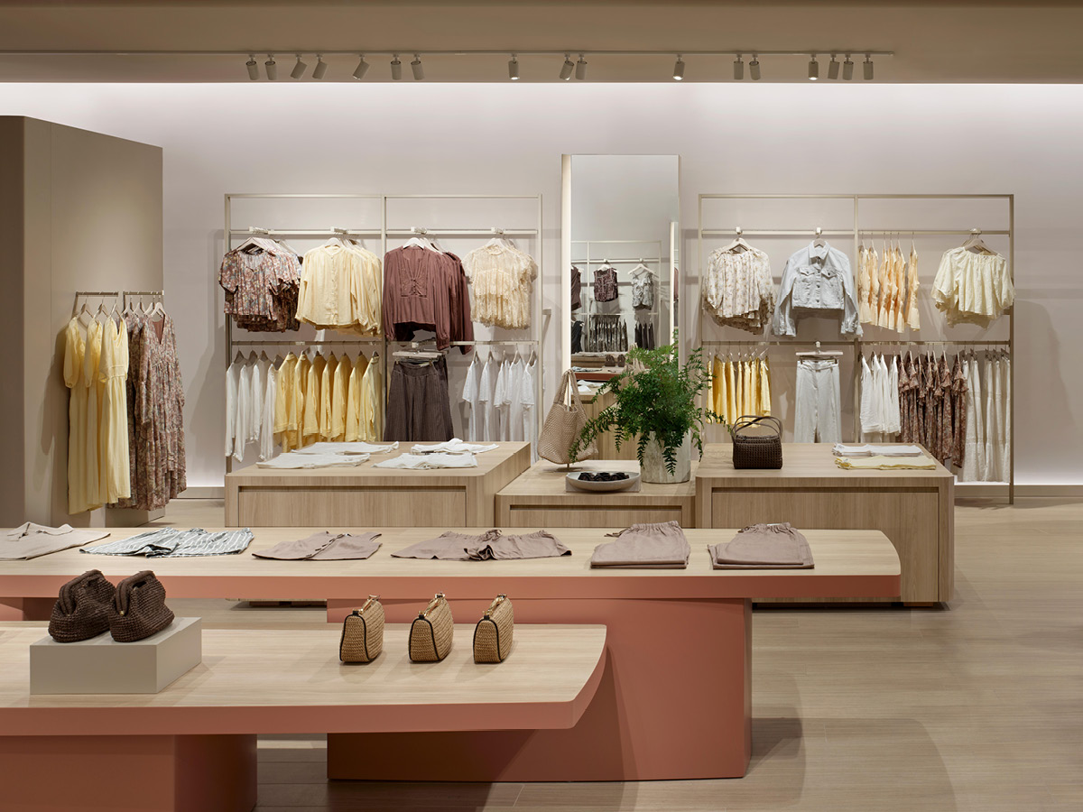 Reitmans fashion displays with central tables and light wood furniture