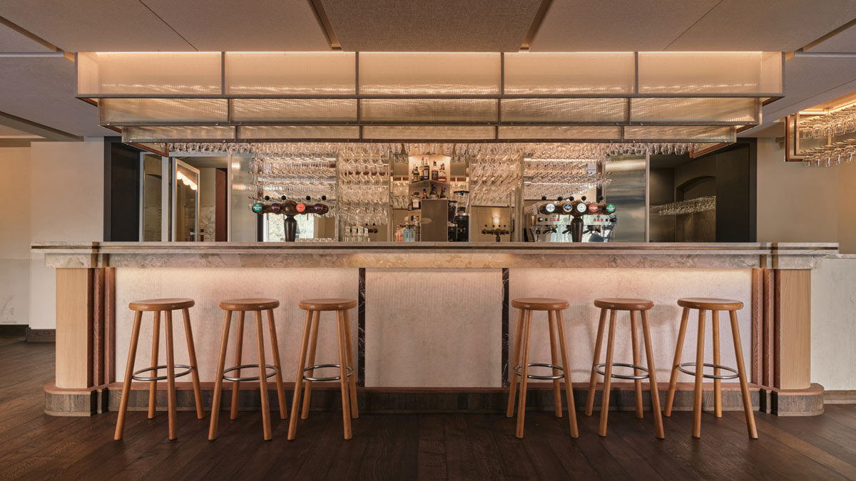 Banco bar centrale di Café Vertigo ad Amsterdam con pietra, legno e struttura sospesa illuminata