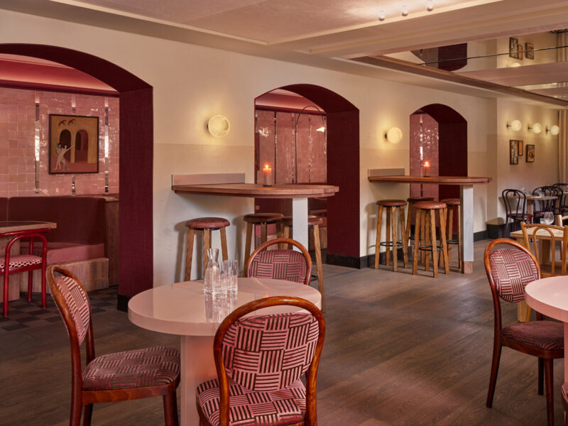 Sala di Café Vertigo ad Amsterdam con nicchie bordeaux, tavoli e sedute bistrot