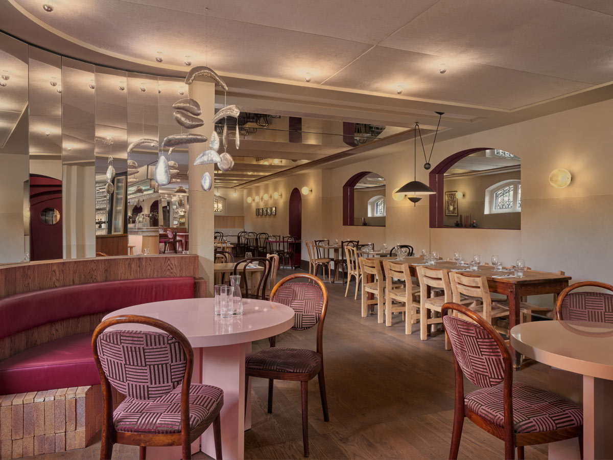 Interno di Café Vertigo con banquette curve, tavoli e installazione sospesa