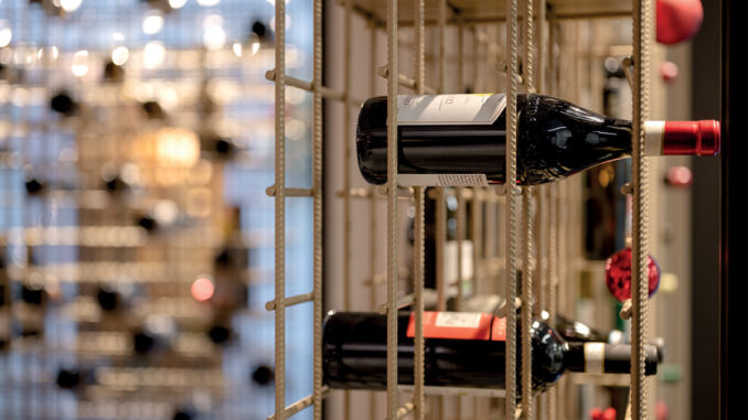 Bottiglie di vino nel sistema espositivo di Enoteca da Aldo a Bolzano
