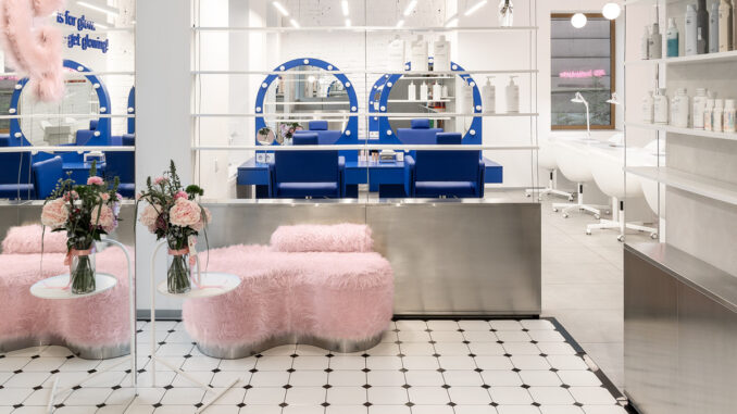 Interno del beauty store G×BAR a Ternopil con arredi blu, seduta rosa e superfici specchianti