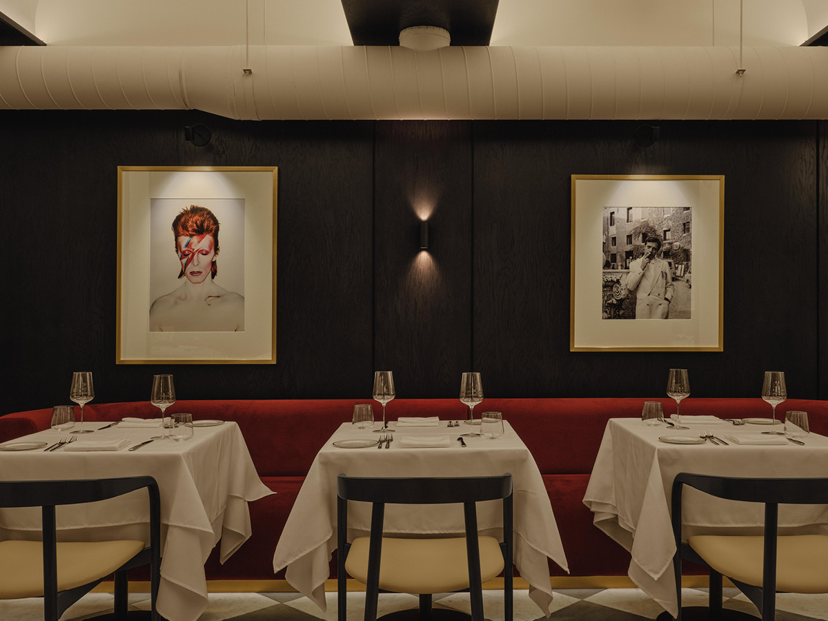 Dining area at Mare restaurant in Montréal with dark walls, photographs and red seating