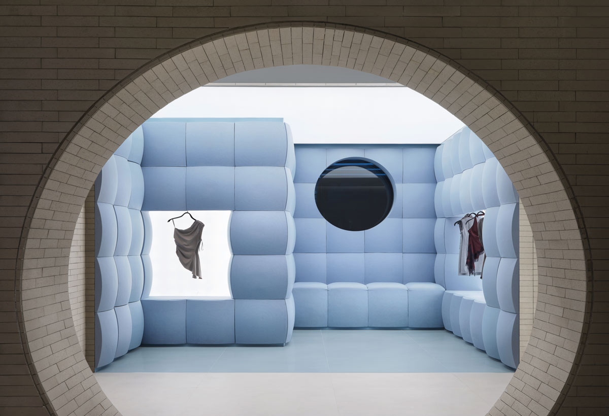 Bold Room azzurra con rivestimenti imbottiti e aperture circolari nel flagship Urban Revivo