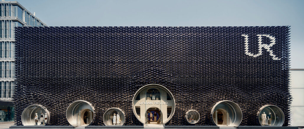Facciata metallica del flagship store Urban Revivo a Pechino progettato da MVRDV, con grandi aperture circolari per ingressi e vetrine.