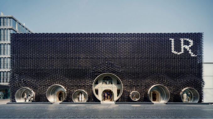 Facciata metallica del flagship store Urban Revivo a Pechino progettato da MVRDV, con grandi aperture circolari per ingressi e vetrine.