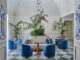 Hall dell’Hotel du Tasso a Sorrento progettata da Antonio Girardi, con sedute blu, specchi veneziani e vegetazione centrale.