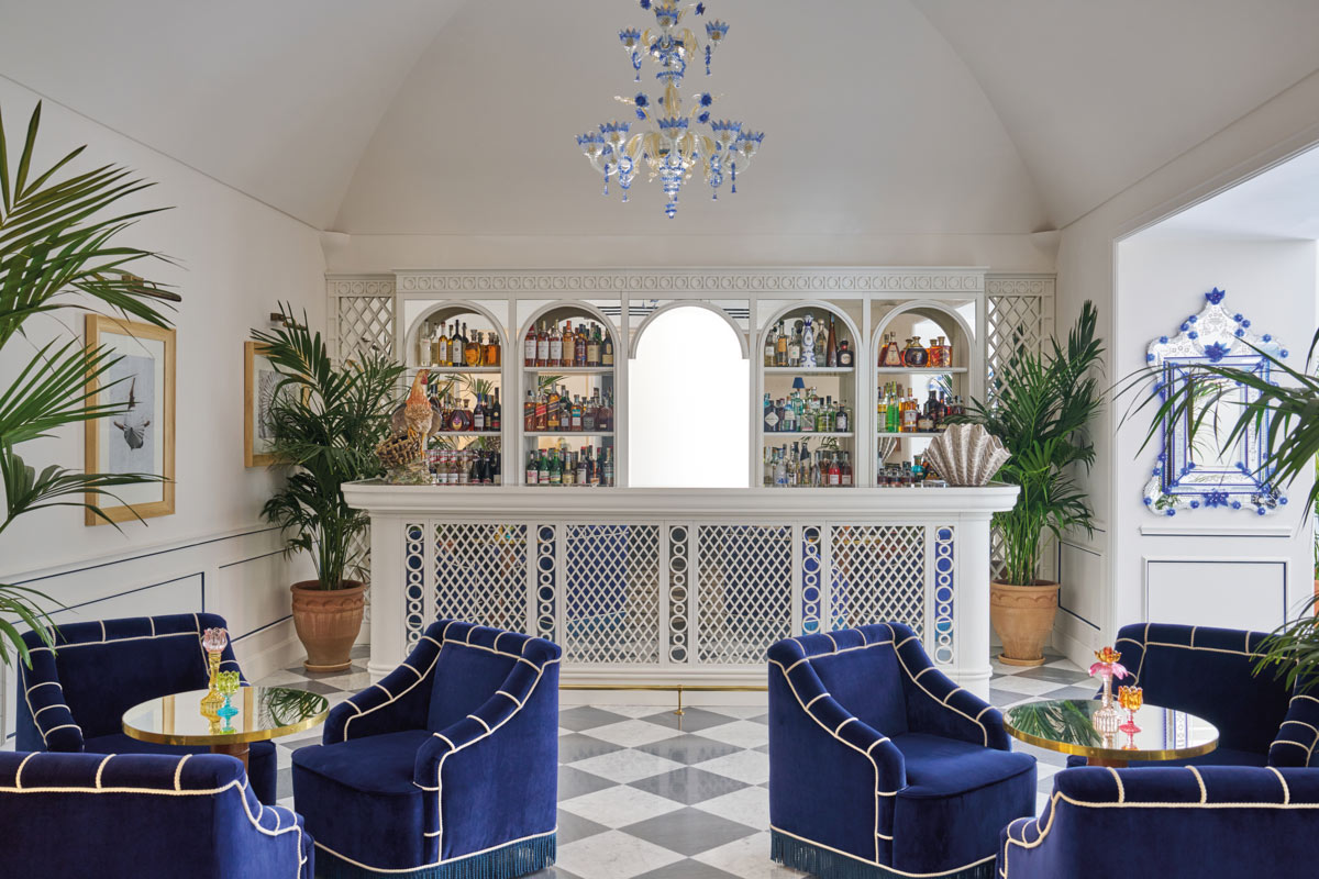 Lounge bar dell'Hotel du Tasso con bancone bianco, poltrone blu e pavimento a scacchiera