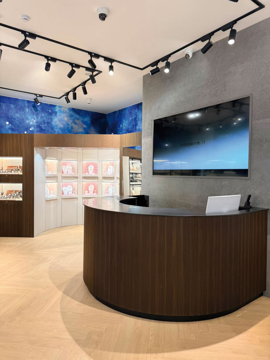 Banco di accoglienza curvo con rivestimento scanalato e schermo integrato nella boutique Intuera Jewellery