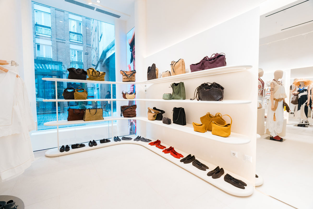 Scaffalature bianche curve con borse e scarpe accanto alla vetrina del negozio Parfois a Milano