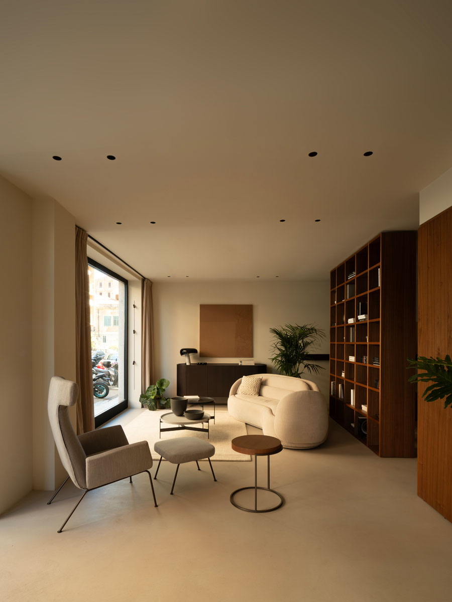 Zona living dello showroom Pianca Palermo con sedute imbottite, tavolini e libreria in legno