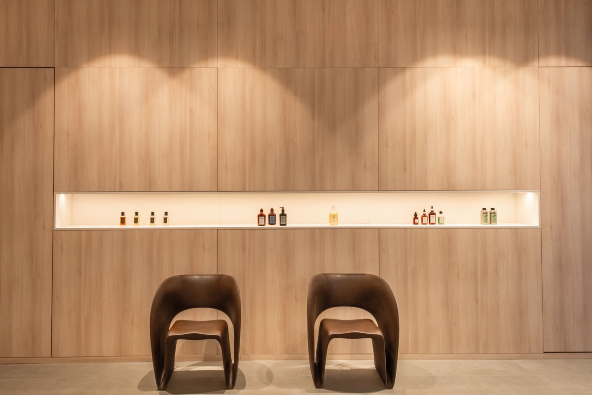 Dettaglio dello showroom D’Asdia a Palermo, rivestimento in rovere con nicchia illuminata e sedute
