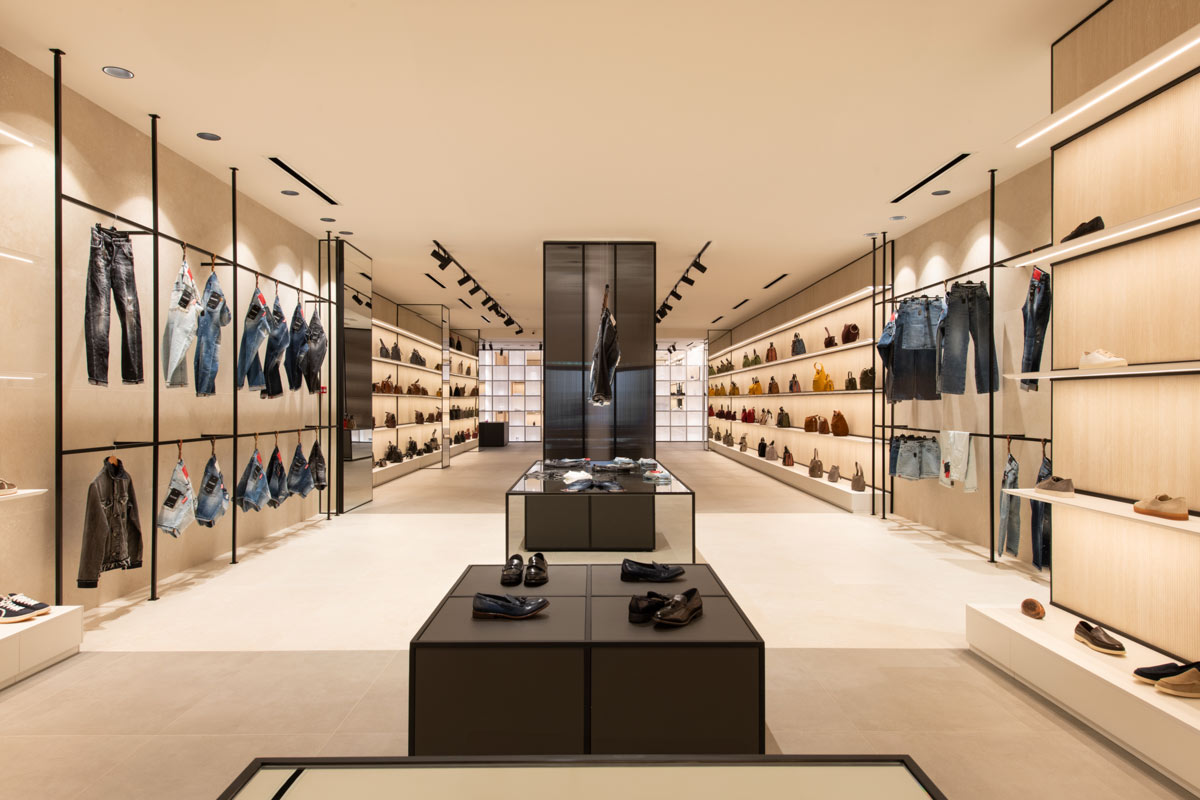 Sistemi espositivi dello showroom D’Asdia con mensole illuminate, quinte architettoniche e seduta centrale