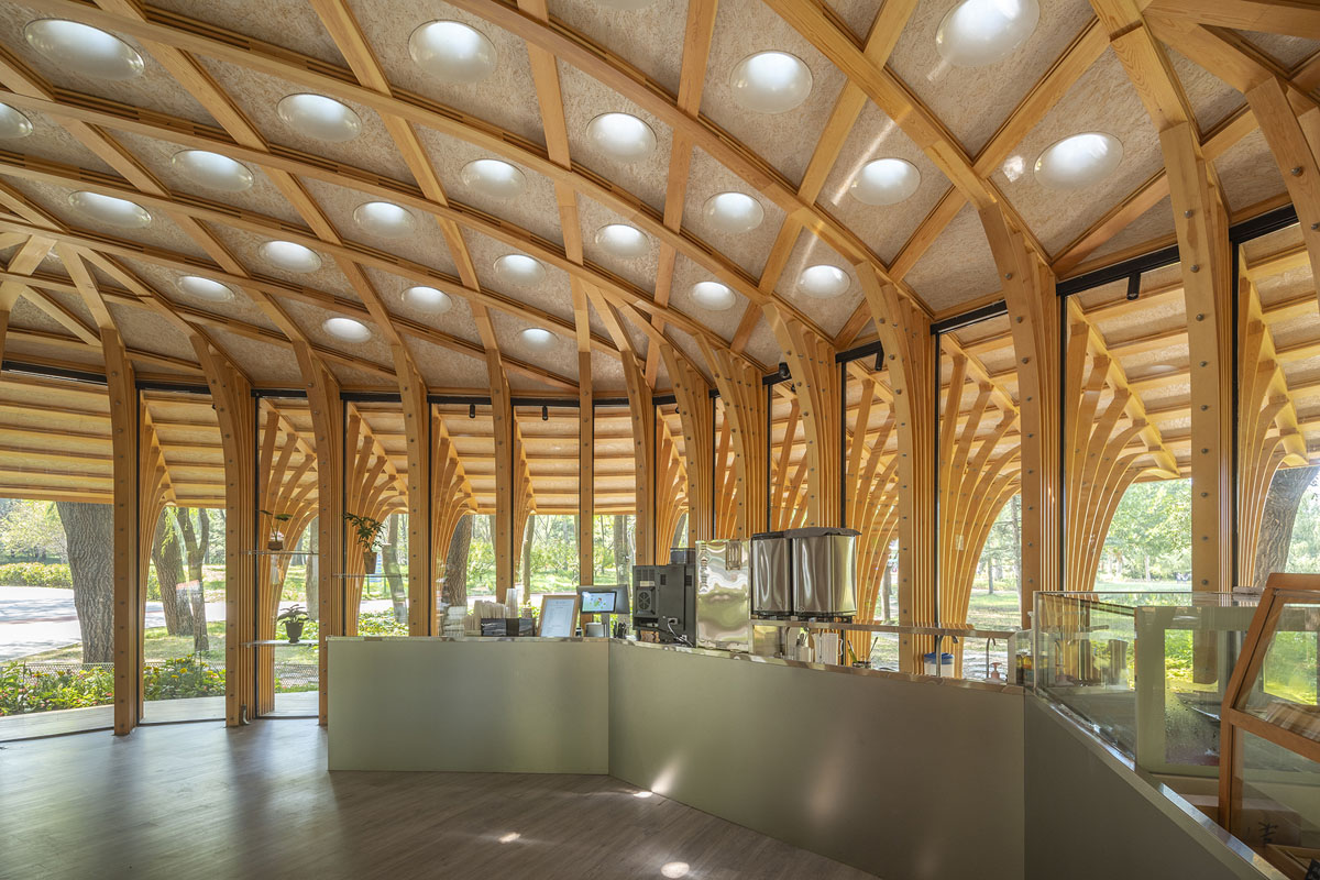 Interno del West Garden Florist con banco di ristoro, pilastri in legno e lucernari circolari nella copertura.